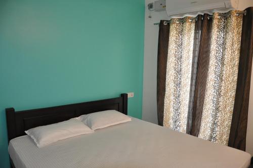 Cama en habitación con pared y cortinas azules en Moonlight Residency en Tiruchchirāppalli