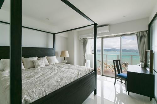 宇流麻Hideout Okinawa Uruma的一间卧室，配有一张床、一张书桌和一扇窗户