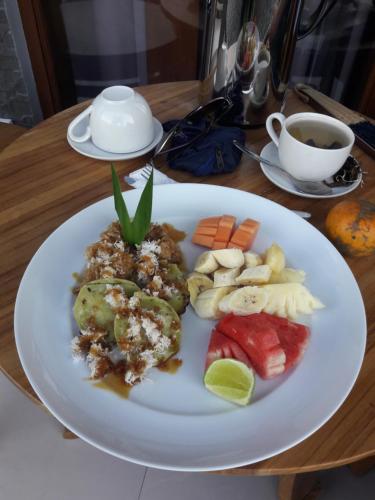 a plate of food with vegetables and fruit on a table at Undis Homestay in Ubud