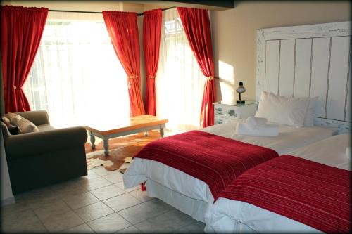 een slaapkamer met een bed, een stoel en ramen bij Aqua Terra Guest House in Lydenburg