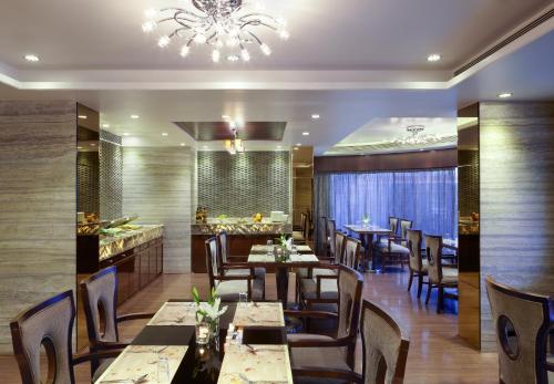 un restaurante con mesas y sillas y una lámpara de araña en Hotel Suba Galaxy Mumbai, en Bombay