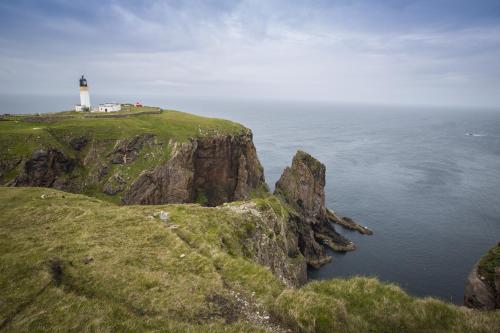 a lighthouse on a cliff next to the ocean at The Hideaway in Lochinver
