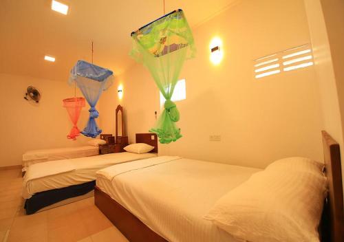 two beds in a room with kites hanging from the wall at Yuthika Resort in Negombo