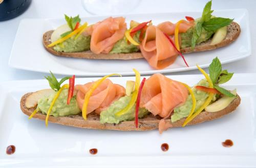 three sandwiches with salmon and vegetables on a plate at Lancaster Eden Bay in Beirut