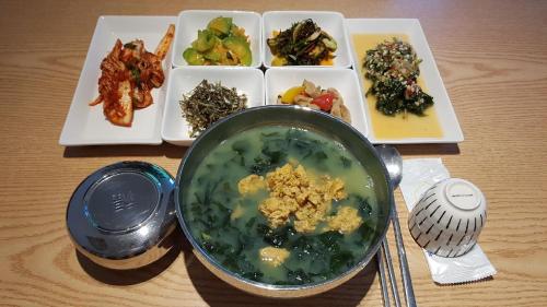 a bowl of soup next to a plate of food at Rezion Hotel in Seogwipo
