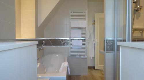 biała łazienka z wanną i prysznicem w obiekcie Best Western Hôtel Montgomery w mieście Pontorson