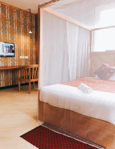 a bedroom with a bed and a tv in a room at Hotel Duomo and Suites in Kampala