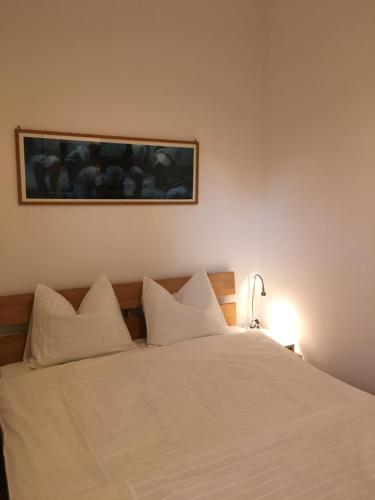 a bed with white sheets and a picture on the wall at Appartement Rainer Sistrans in Innsbruck