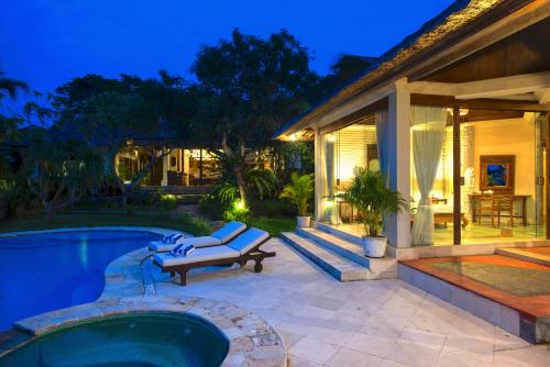 a house with a pool and a bench next to a house at Casa Jimbaran Villa in Jimbaran