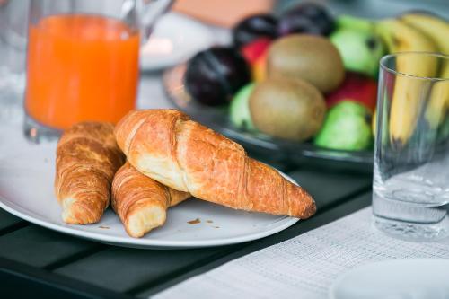 a plate of croissants and fruit on a table at Penelope Corfu Suite in Corfu Town