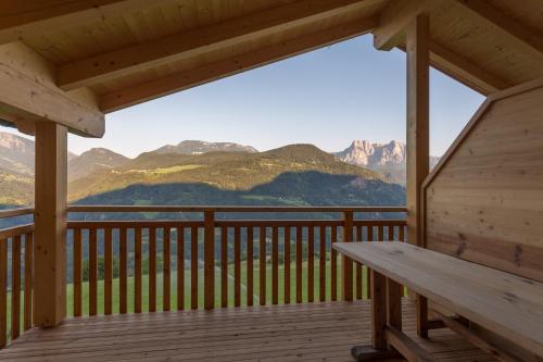 a wooden porch with a bench on a deck with mountains at Frühaufhof in Barbiano