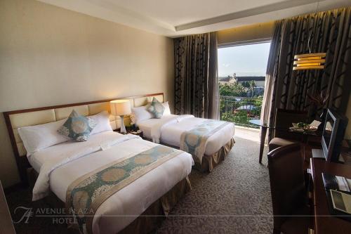 um quarto de hotel com duas camas e uma janela em The Avenue Plaza Hotel em Naga