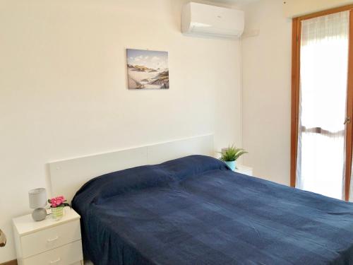 a white bedroom with a blue bed and a window at Residence Viale del Sole in Grado