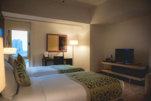 マナーマにあるAsdal Gulf Inn Boutique Hotel- SEEFのベッド2台、薄型テレビが備わるホテルルームです。