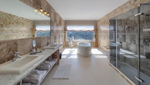 een badkamer met 2 wastafels, een bad en een douche bij Los Cinco Enebros in Robledo de Chavela