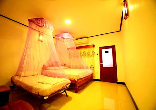 a bedroom with two beds with mosquito nets at Yuthika Resort in Negombo