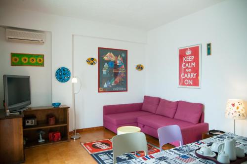 a living room with a pink couch and a table at Mediterraneo Guesthouse in Giardini Naxos
