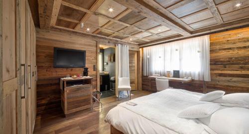 a bedroom with a bed and a flat screen tv at Hostellerie du Pas de l'Ours "Relais et Châteaux" in Crans-Montana