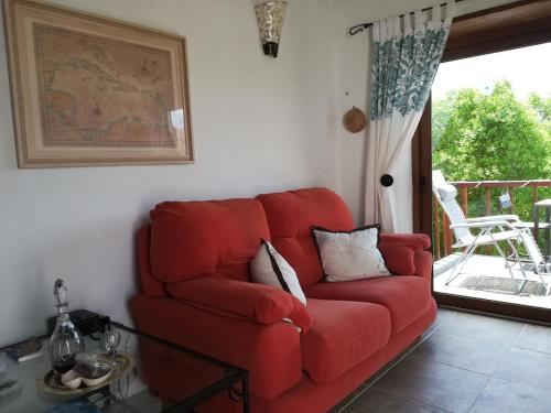 a red couch in a living room with a balcony at Quinta do Bom Vento in Óbidos