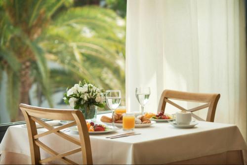 a table with a plate of food and wine glasses at Inturotel Cala Azul in Cala d´Or