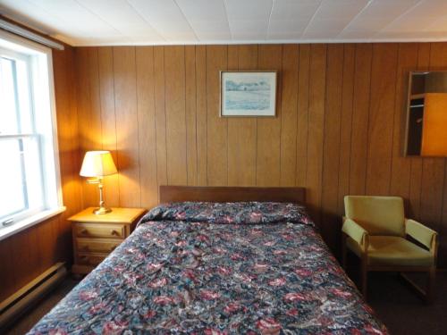a bedroom with a bed and a chair and a window at Hipwell's Motel in Fonthill