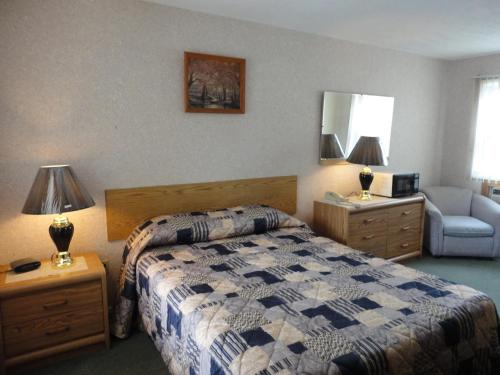ein Schlafzimmer mit einem Bett, einem Sofa und einem Stuhl in der Unterkunft Hipwell's Motel in Fonthill