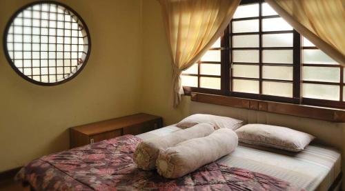 1 Schlafzimmer mit einem Bett mit Kissen und 2 Fenstern in der Unterkunft Villa Kota Bunga Ade Type Jepang - 0620 in Cibadak