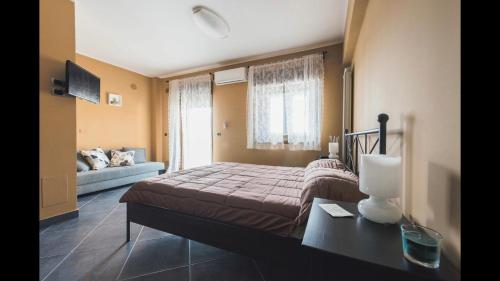 B&B Terrazza dell'Etna في ماسكالوتشا: غرفة نوم بسرير واريكة