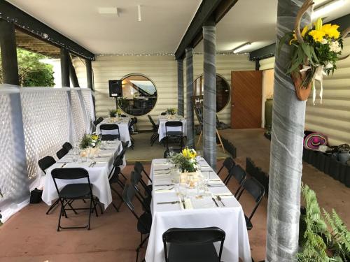 a room with white tables and chairs with flowers at Tipi and Bobs Waterfront Lodge in Tryphena
