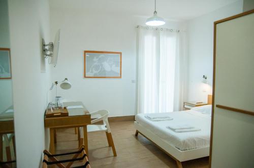 a bedroom with a bed and a desk and a table at Mediterraneo Guesthouse in Giardini Naxos
