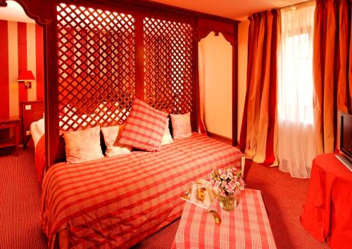 a bedroom with a bed and a table with flowers on it at Hotel Restaurant L'Ami Fritz in Ottrott
