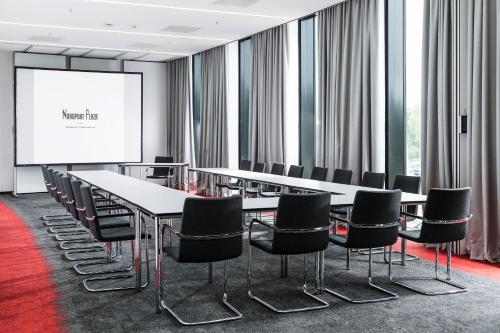 a conference room with tables and chairs and a screen at Airport Plaza Hotel Hamburg in Norderstedt