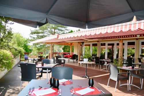 an outdoor restaurant with tables and chairs and an umbrella at Relais Vosgien - Hôtel Restaurant "la Table de Sophia" in Saint-Pierremont