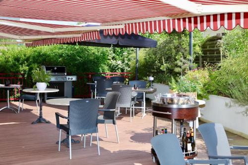 a patio with tables and chairs and an umbrella at Relais Vosgien - Hôtel Restaurant "la Table de Sophia" in Saint-Pierremont