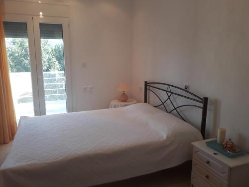 1 dormitorio con cama blanca y ventana en The green garden villa by the sea!, en AgiaKampos