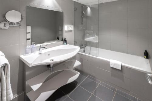 a white bathroom with a sink and a tub at Aparthotel Adagio Nice Promenade des Anglais in Nice