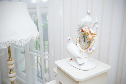 a clock with two white birds sitting on a table at Pałac Brzeźno Spa & Golf in Oborniki Śląskie