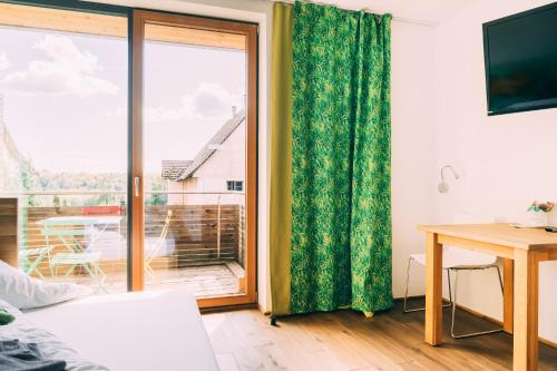 a room with a sliding glass door with a desk and a table at Gut Hügle Erlebnishof in Ravensburg