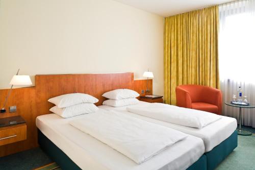 a bedroom with a large bed and a red chair at Mercure Hotel am Messeplatz Offenburg in Offenburg
