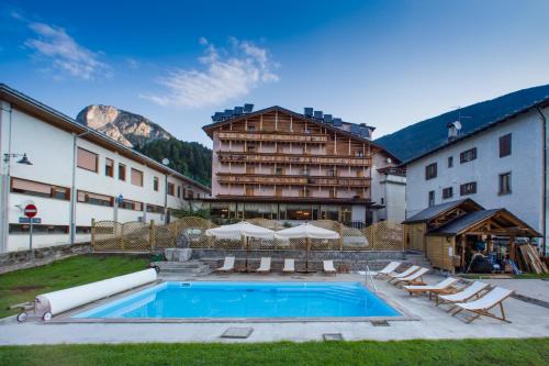 a hotel with a swimming pool in front of a building at Hotel Posta in Forni di Sopra