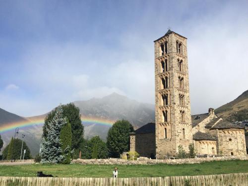 a person standing in front of an old building with a rainbow at Hostal Rural Sant Climent - Habitacions i Apartaments in Taull
