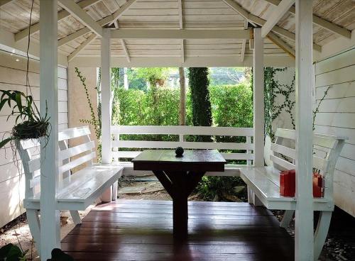a porch with two white benches and a table at Reera Resort in Hua Hin