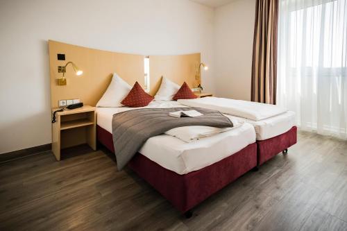 a hotel room with a large bed and a desk at City-Hotel garni in Neu Ulm