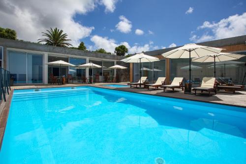 a large swimming pool with chairs and umbrellas at Mosteiros Place in Mosteiros