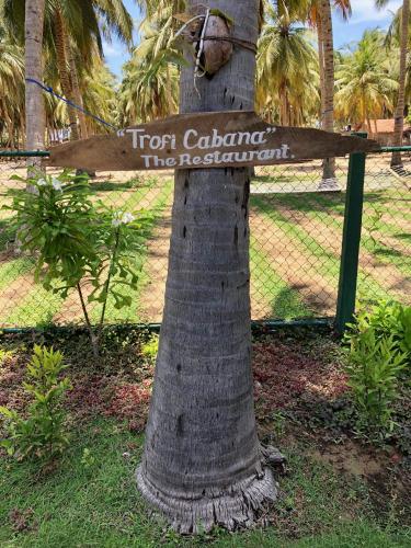 a sign on a tree in front of a fence at Wind Blend Kite Resort in Kalpitiya