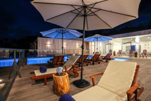 a deck with chairs and umbrellas next to a pool at Mosteiros Place in Mosteiros