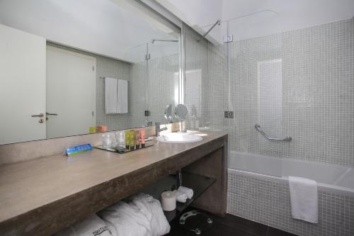a bathroom with a sink and a mirror and a tub at Mosteiros Place in Mosteiros