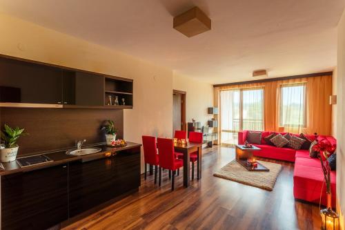 a living room with a red couch and a kitchen at Top Apartment in Bansko in Bansko