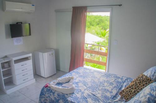 1 dormitorio con 1 cama y ventana con TV en Pousada Acuípe en Olivença