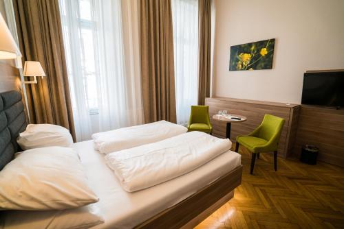 a hotel room with two beds and a television at Hotel Marc Aurel - Vienna City Center in Vienna